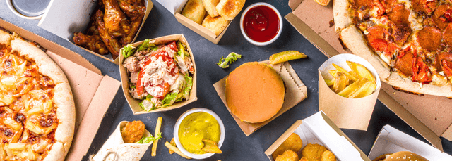 Overhead view of diverse takeout meal spread including pizza, burger, wings, fries, and salad in delivery containers