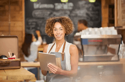 Woman smiling holding tablet in a cafe