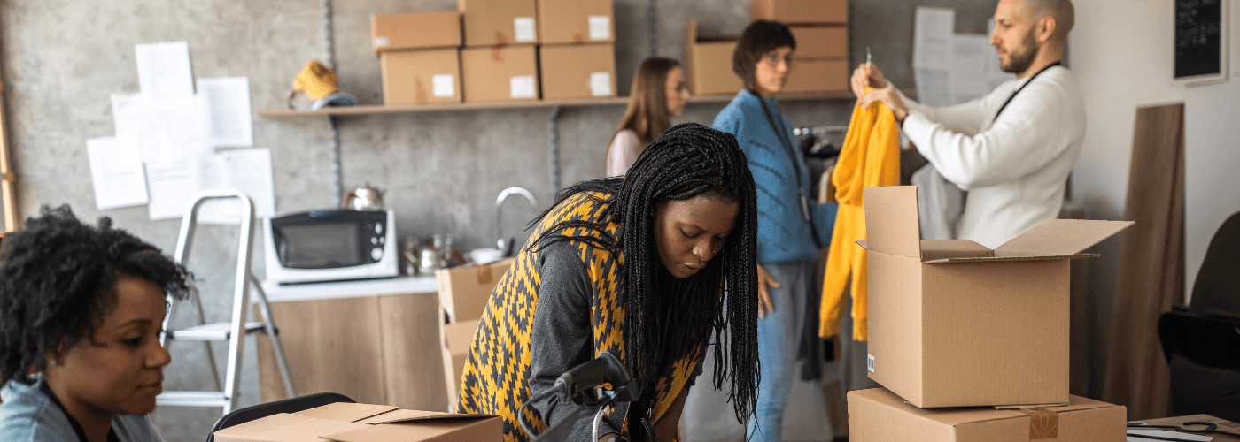 E-commerce fulfillment team packaging and preparing orders in warehouse with cardboard boxes and shipping materials